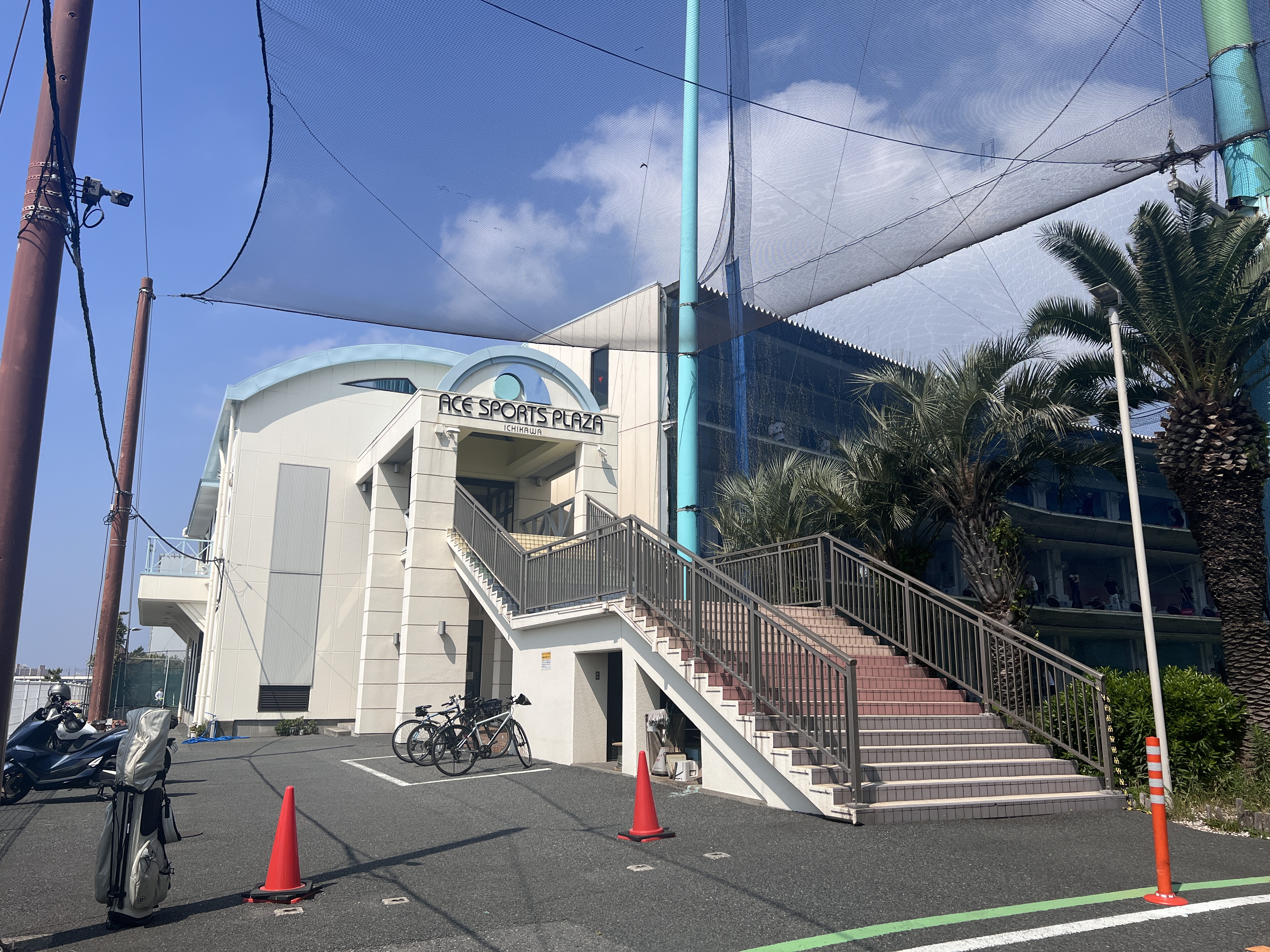 エーススポーツプラザ市川の外観と入口階段、青空に伸びるネット