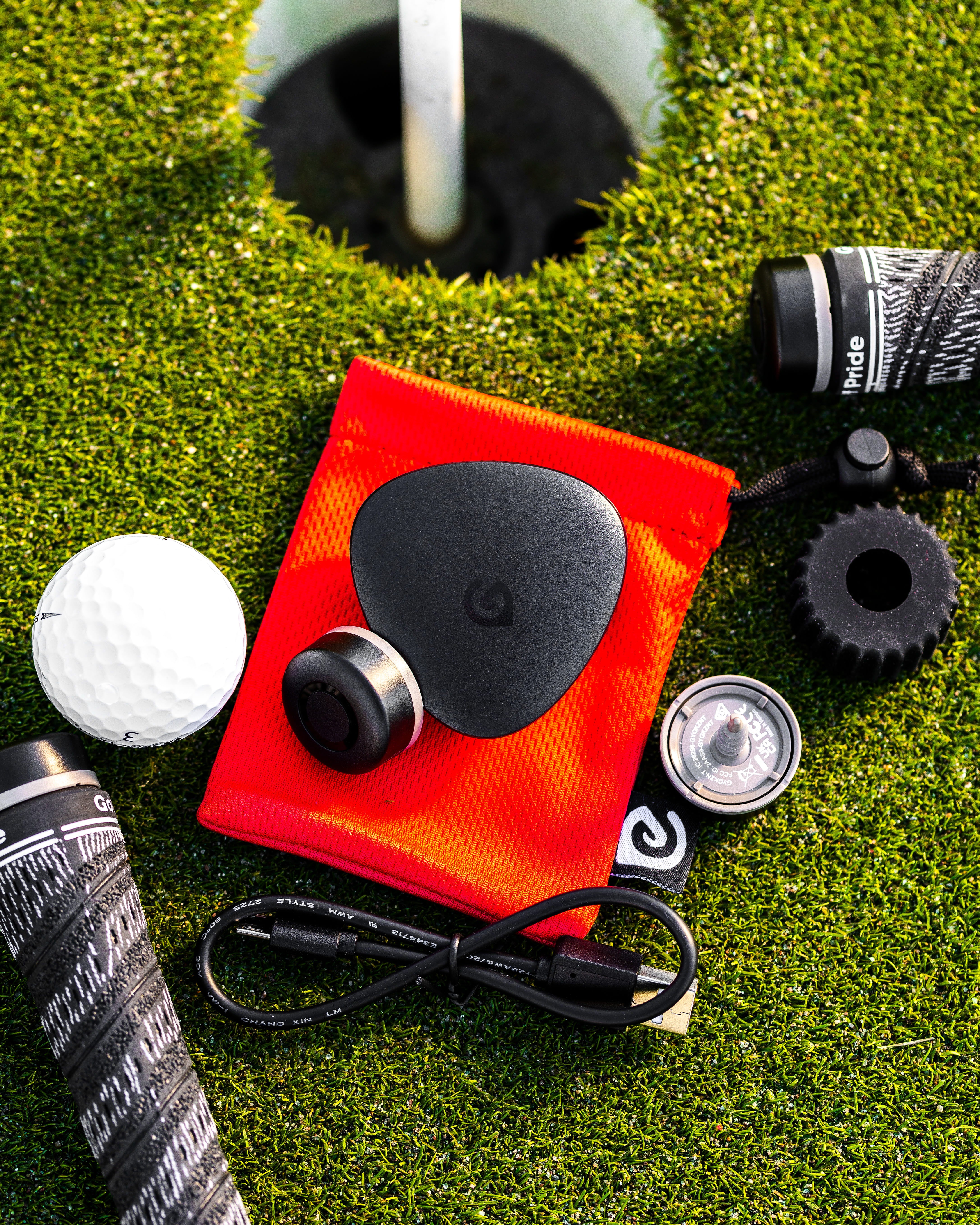 GameGolfのクラブセンサーとGPSユニット、専用ポーチが芝生の上に置かれている
