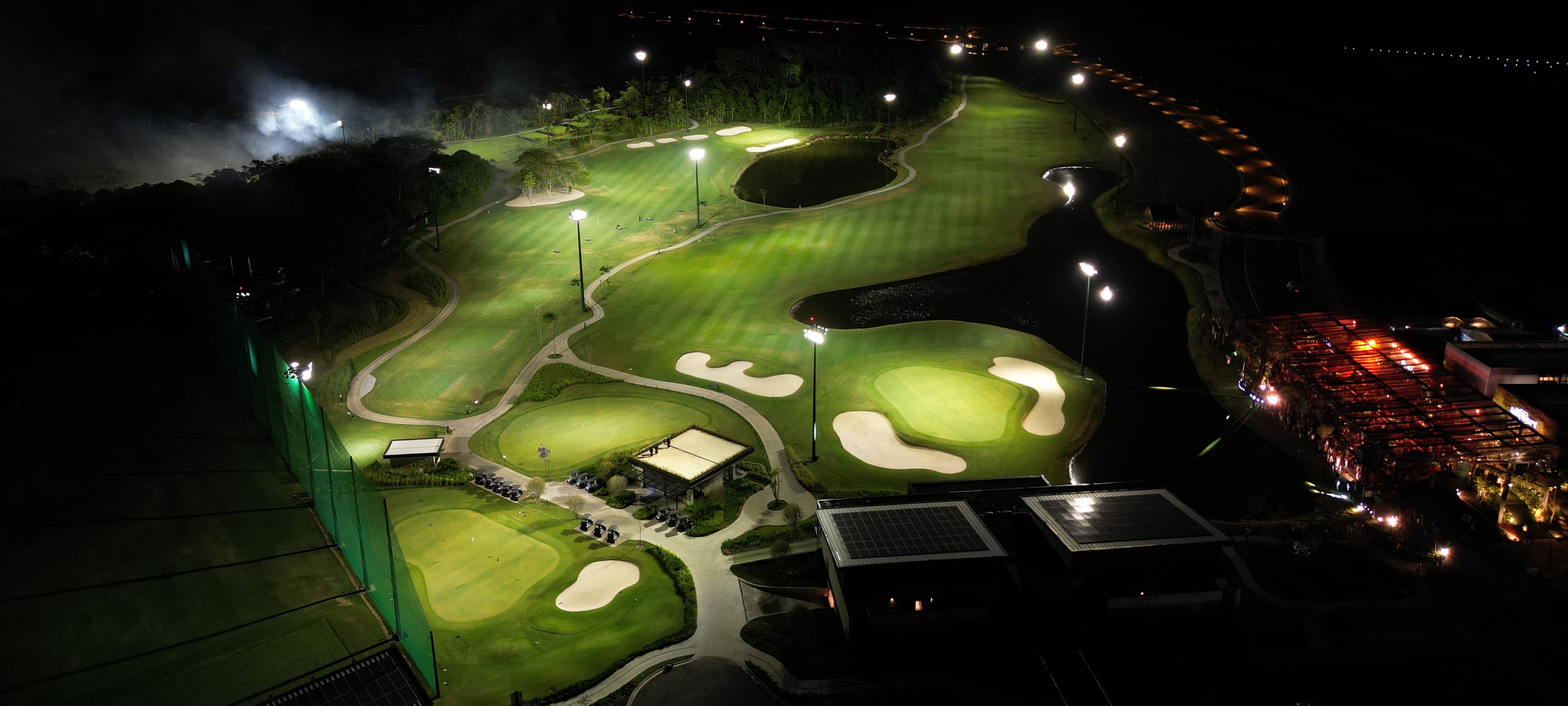 夜間照明で点灯したPorto Belo Golfの空撮。フェアウェイを照らすLED照明柱と、クラブハウス屋根の太陽光パネルが見える