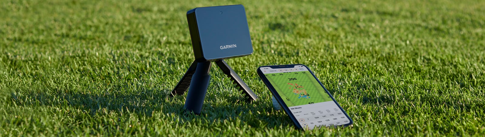 芝の上に三脚マウントで置いたGarmin Approach R10と、ショットの分散チャートを表示したスマートフォン
