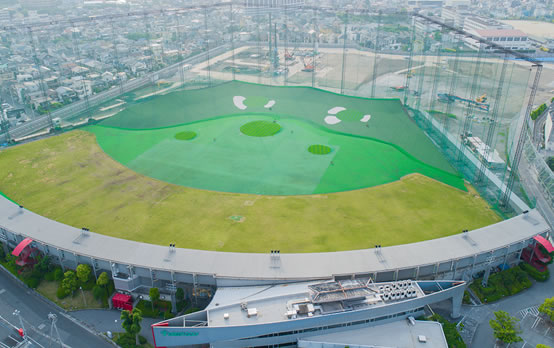 川口グリーンゴルフ レンジ全景の空撮(3階建て打席の弧状配置)